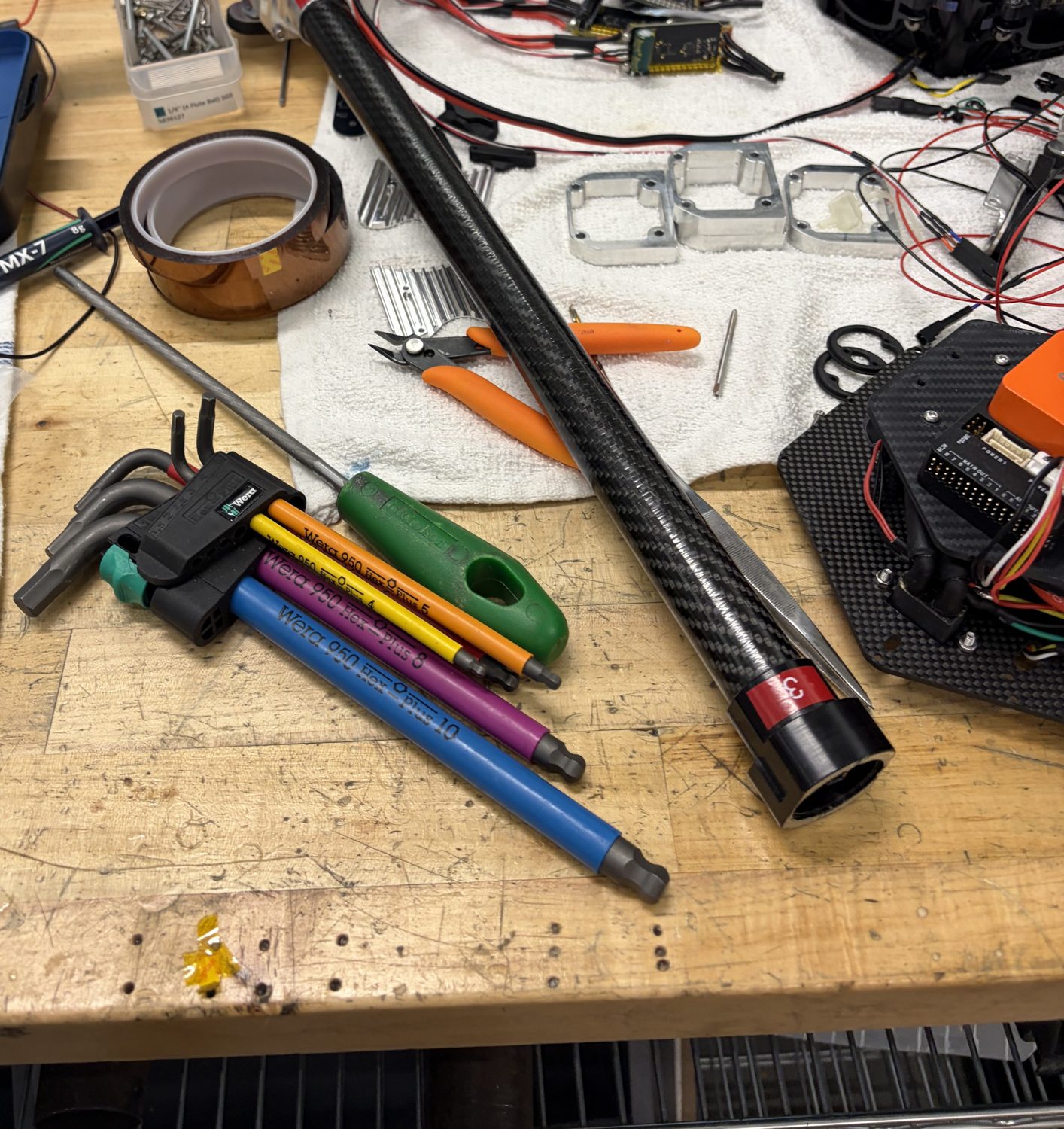 A carbon tube arm with motor and parts laid out on the workbench