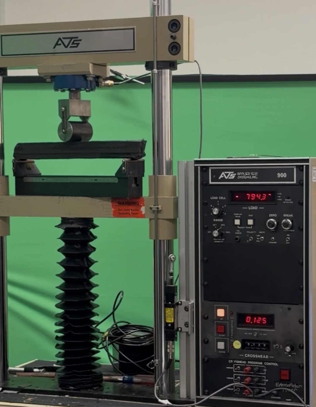 The composite beam loaded in a three-point bending fixture on a materials testing machine
