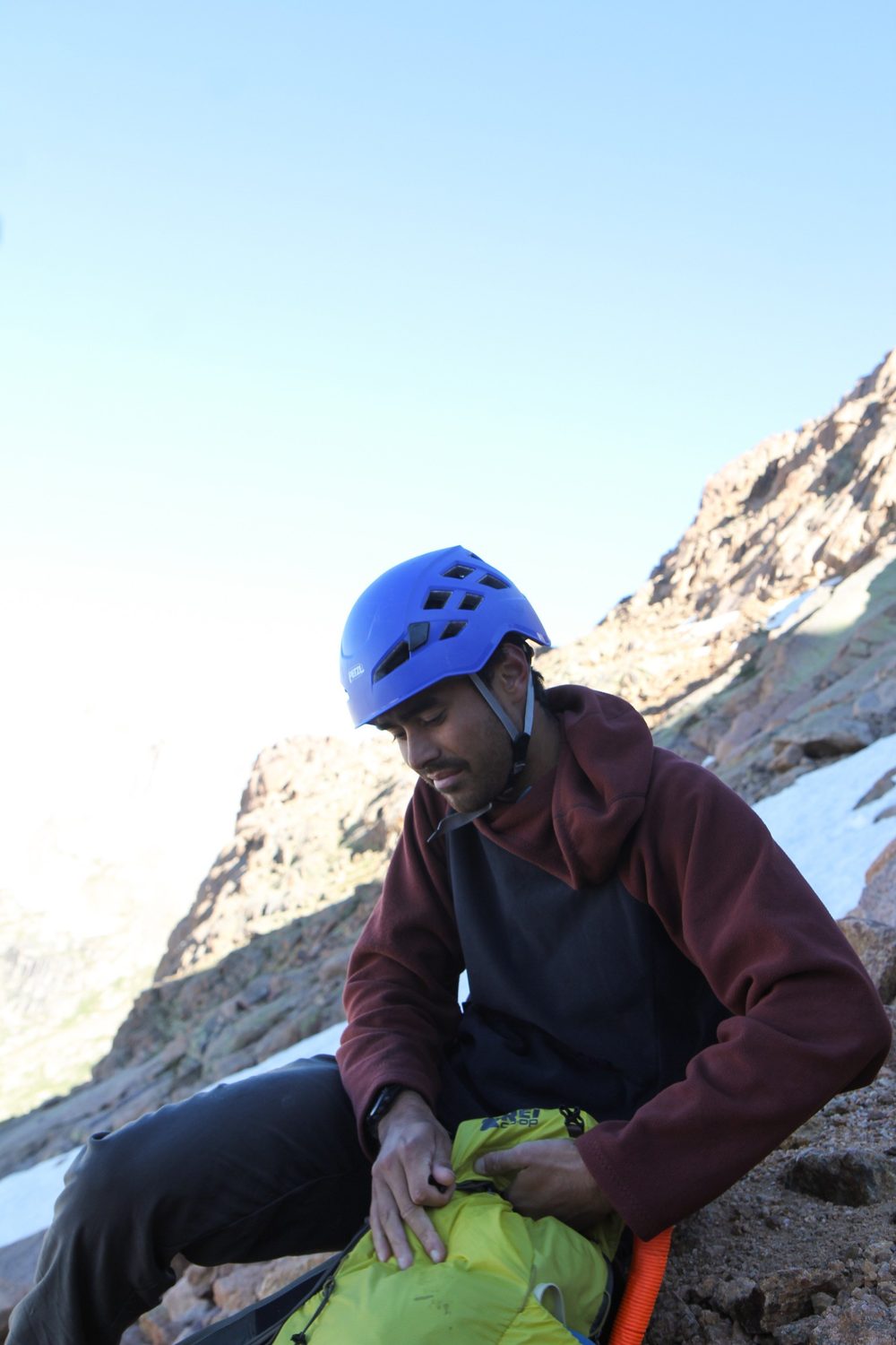 Wallace in a climbing helmet resting on a mountain slope