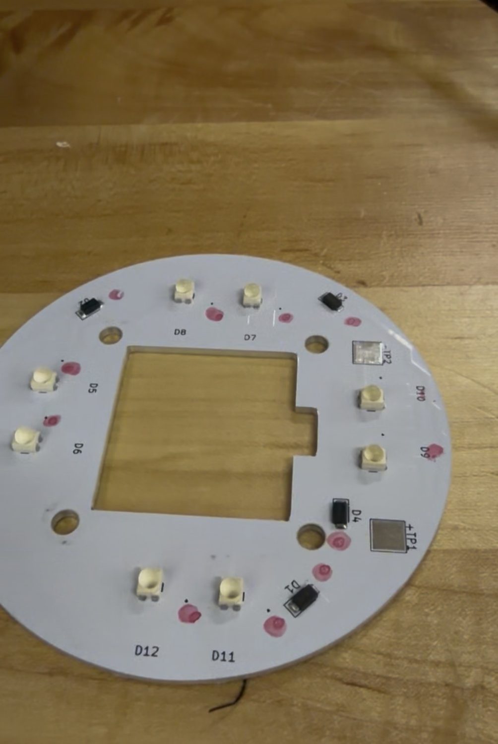 A populated round LED circuit board with a square center cutout