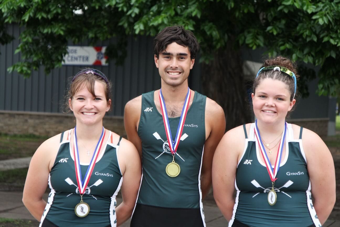 Wallace smiling with a gold medal between two teammates